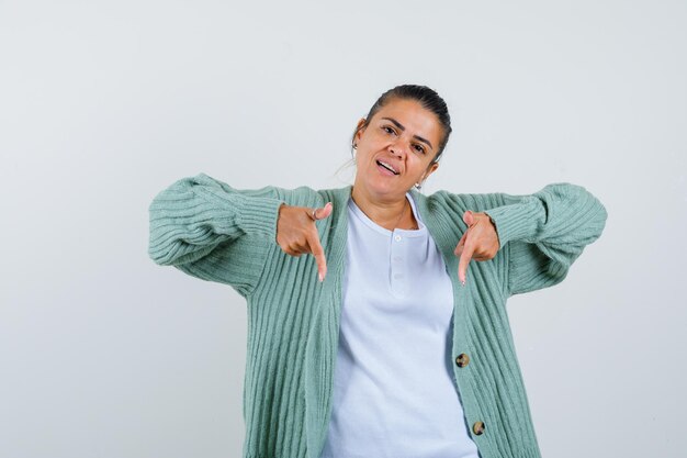 Jeune femme pointant vers le bas en t-shirt, veste et à l'air confiant