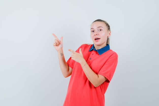 Jeune femme pointant vers le coin supérieur gauche en t-shirt et à la jolly