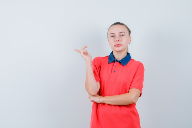 Jeune femme pointant vers le côté en t-shirt et à la confiance