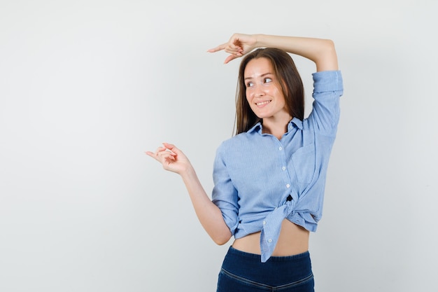 Jeune femme pointant vers l'extérieur en chemise bleue, pantalon et à l'espoir