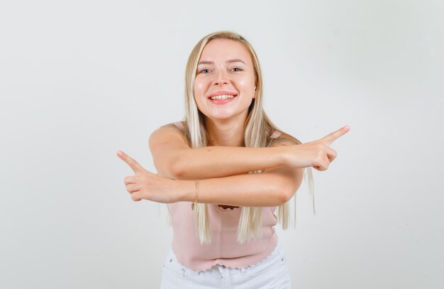 Jeune femme pointant vers l'extérieur en maillot, mini jupe et à la joyeuse.