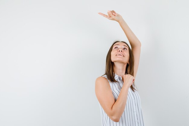 Photo gratuite jeune femme pointant vers l'extérieur en t-shirt et regardant focalisée, vue de face