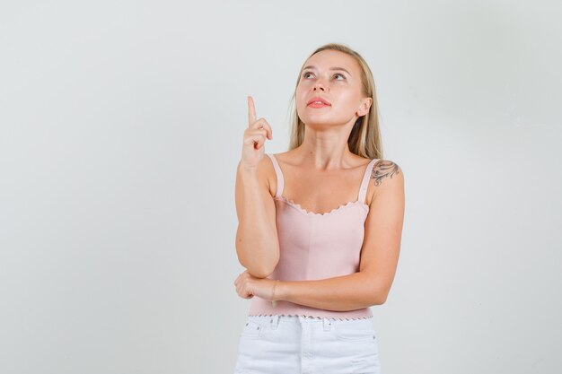 Jeune femme pointant vers le haut du doigt en maillot