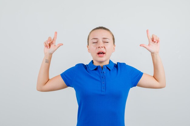 Jeune femme pointant vers le haut en t-shirt bleu et à la recherche d'espoir