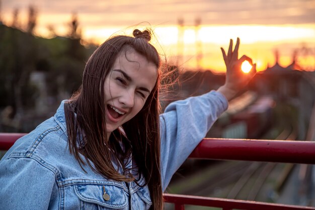 Une jeune femme sur le pont, posant à un beau coucher de soleil.