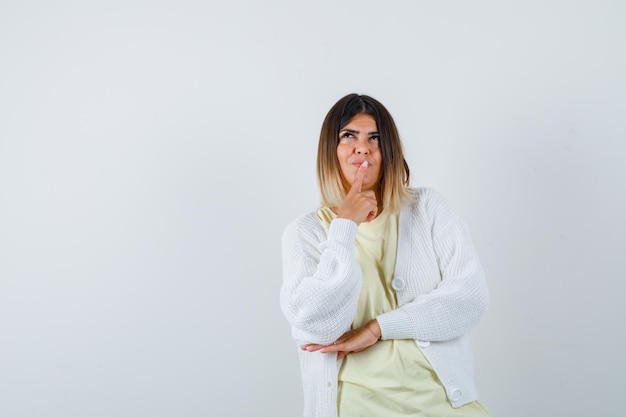 Jeune femme portant un cardigan blanc pensant