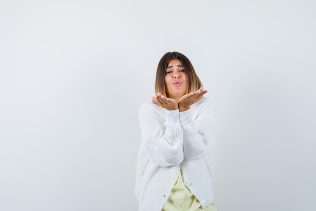 Jeune femme portant un cardigan blanc soufflant un baiser