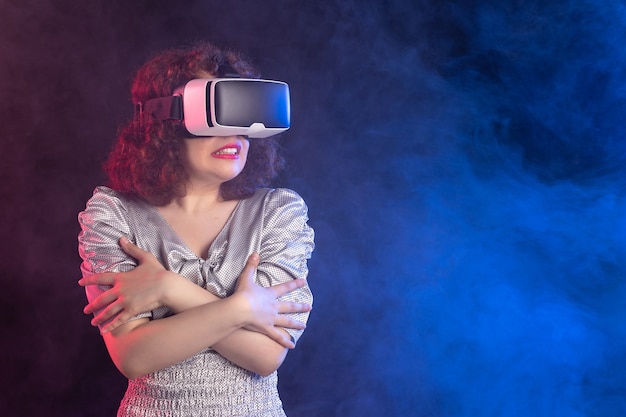 Jeune femme portant un casque de réalité virtuelle sur une surface bleu foncé