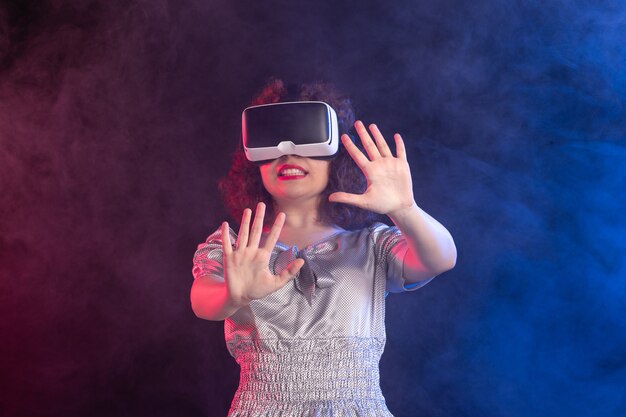 Jeune femme portant un casque de réalité virtuelle sur une surface bleu foncé