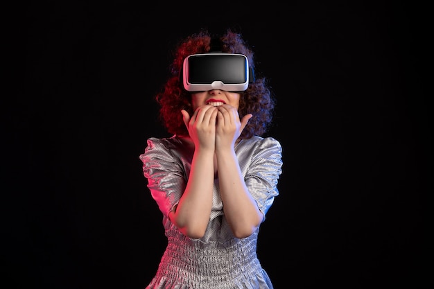 Jeune femme portant un casque de réalité virtuelle sur une surface sombre