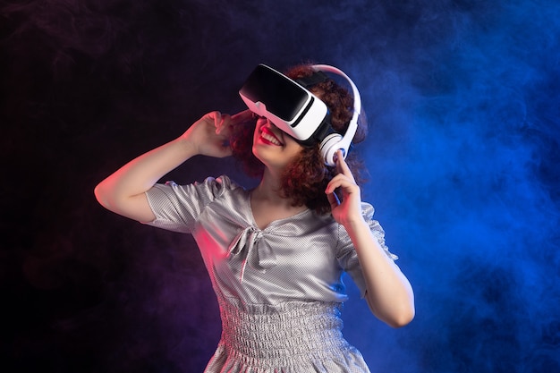 Jeune femme portant un casque vr dans des écouteurs sur une surface bleu foncé