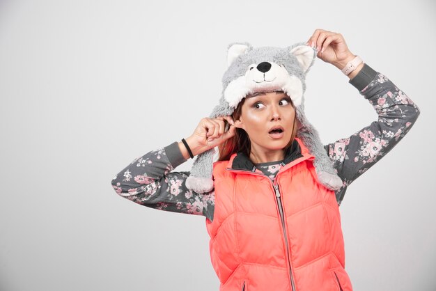 Jeune femme portant un chapeau drôle sur un mur blanc