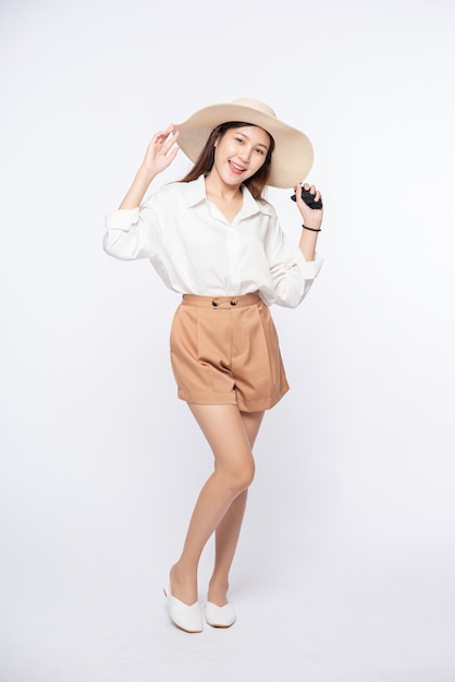 Jeune femme portant une chemise blanche et un short, portant un chapeau et une poignée sur le chapeau