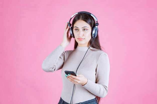 Jeune femme portant des écouteurs et réglage de la musique sur son smartphone