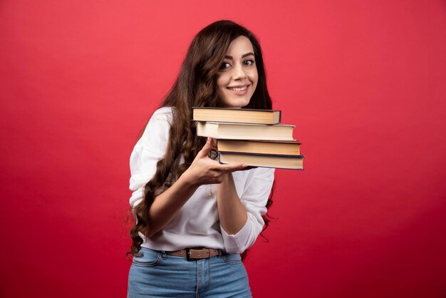 Jeune femme portant des livres sur fond rouge. photo de haute qualité