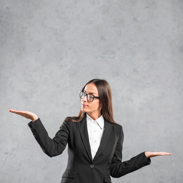 Jeune femme portant des lunettes présentant sur fond gris