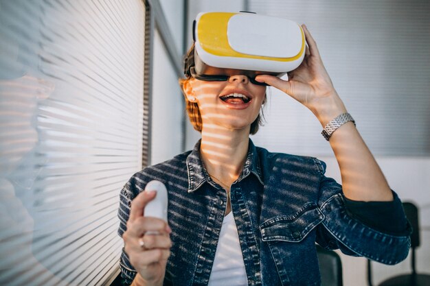 Jeune femme portant des lunettes de réalité virtuelle et jouant à un jeu virtuel en utilisant une télécommande