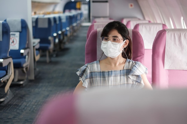 Jeune femme portant un masque protecteur dans l'avion ou les transports en commun, protection infection par la maladie à coronavirus, touriste asiatique prêt à voyager. suivant concept normal et réouverture