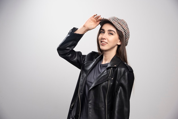 Jeune femme portant une veste en cuir noir et une casquette.