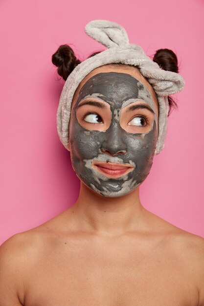 Jeune femme porte des traitements de la peau de masque d'argile du visage naturel après avoir pris un bain