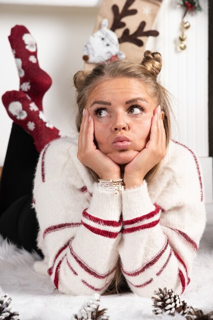 Une jeune femme posant allongée sur un tapis à l'intérieur de Noël.