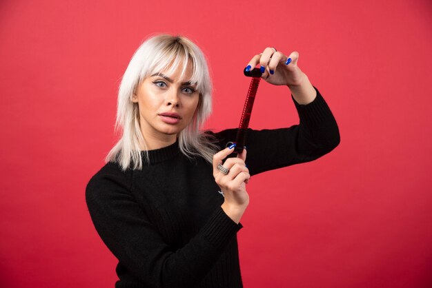 Jeune femme posant avec une bande photo sur fond rouge