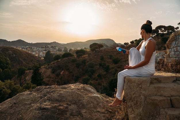 Jeune femme posant avec une bouteille d&#39;eau dans la nature