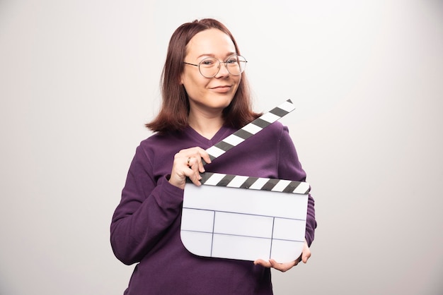 Jeune femme posant avec une cassette de cinéma sur fond blanc. photo de haute qualité