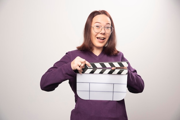 Jeune femme posant avec une cassette de cinéma sur fond blanc. photo de haute qualité