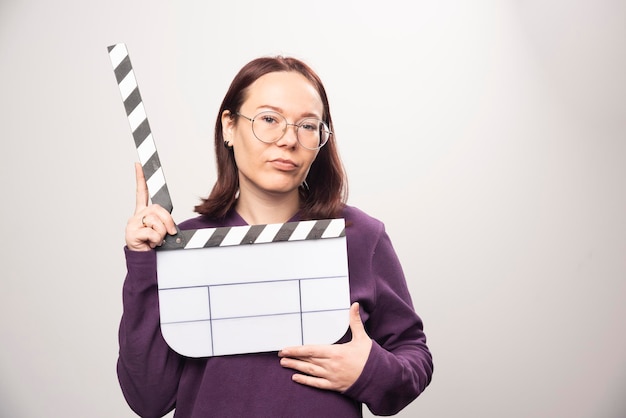 Jeune femme posant avec une cassette de cinéma sur fond blanc. photo de haute qualité