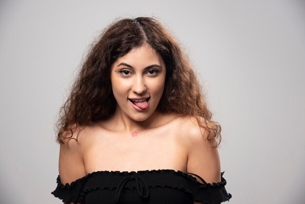 Jeune femme posant en chemisier noir aux cheveux bouclés. Photo de haute qualité