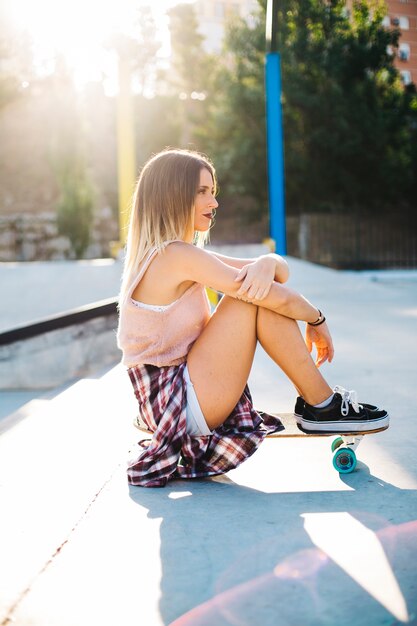 Jeune femme posant cool avec un balai de skatboard
