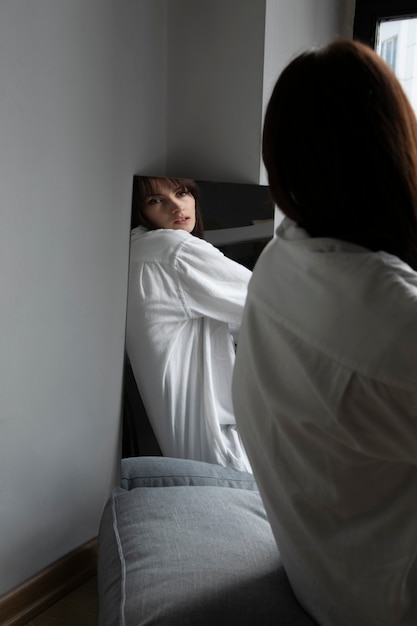 Jeune femme posant à côté d'un miroir créant une réflexion