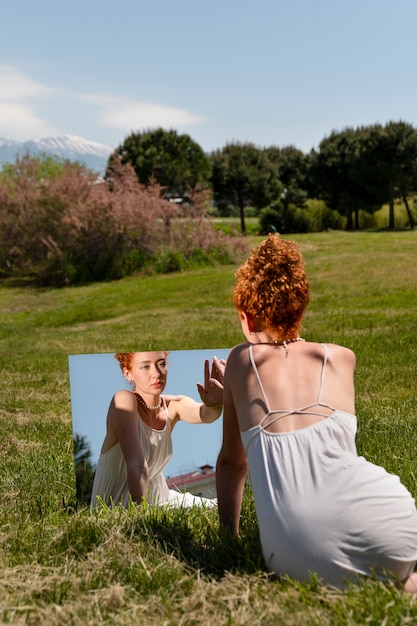 Photo gratuite jeune femme posant dans le miroir sur l'herbe à l'extérieur