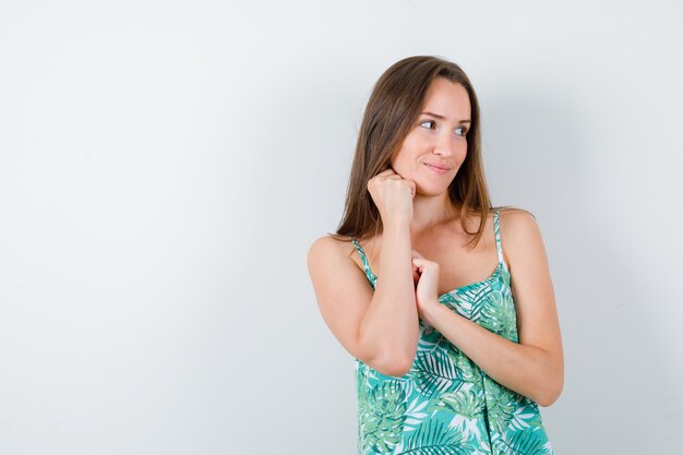 Jeune femme posant debout en chemisier et magnifique, vue de face.