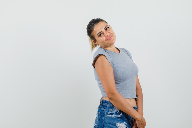 Jeune femme posant debout en t-shirt, short et jolie