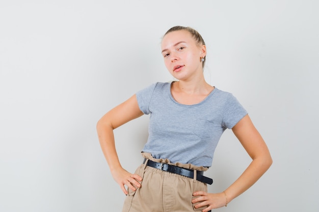 Jeune femme posant debout en t-shirts et pantalons et à la belle