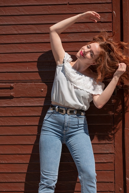 Photo gratuite jeune femme posant devant la porte marron