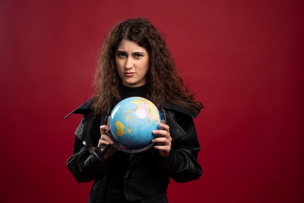 Jeune femme posant avec globe.