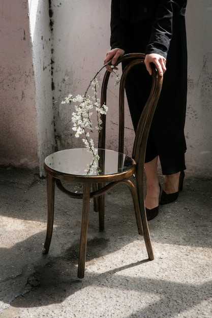 Jeune femme posant avec miroir sur chaise et fleur