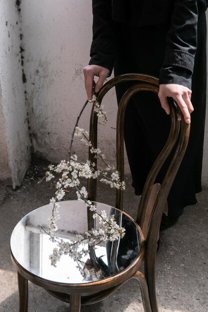 Jeune femme posant avec miroir sur chaise et fleur