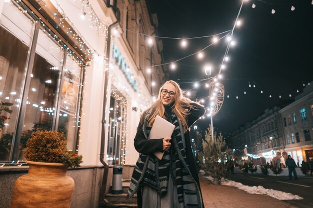 Jeune femme posant avec un ordinateur portable dans la rue