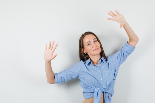 Jeune femme posant avec des palmiers surélevés en chemise bleue et à l'optimiste