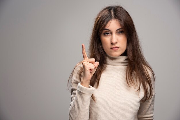 Une jeune femme posant et pointant l'index de côté vers le haut.