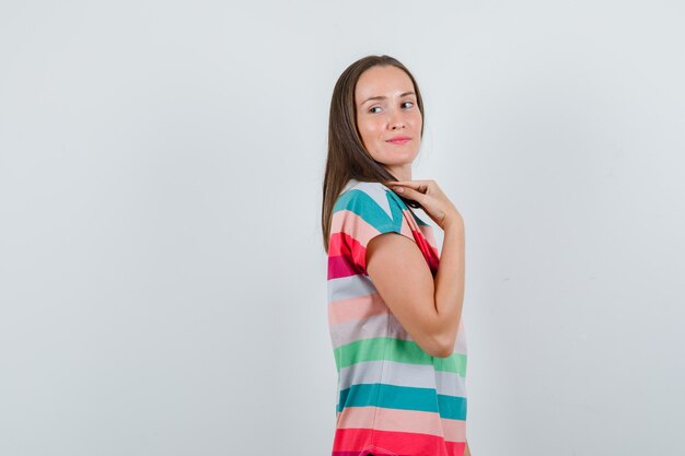 Jeune femme posant en regardant en arrière en t-shirt et à la recherche de charme. .