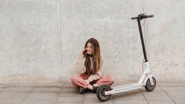 Jeune femme posant avec un scooter électrique