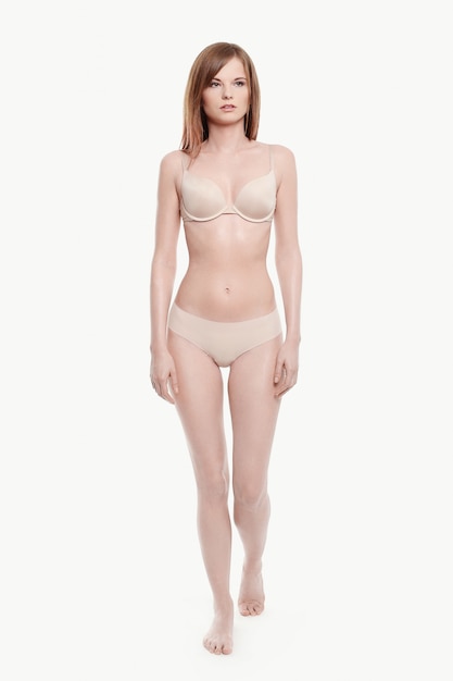 Jeune femme posant en sous-vêtements, soutien-gorge et culotte beige, peau parfaite