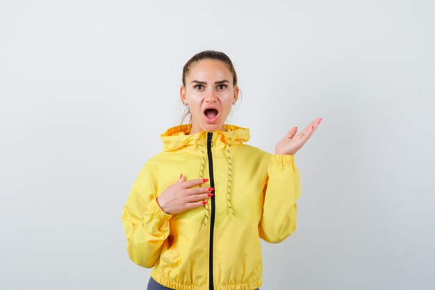 Jeune femme posant en veste jaune et à la perplexité, vue de face.