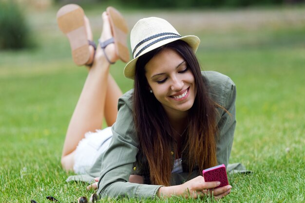 Jeune femme pose dans l&#39;herbe avec téléphone