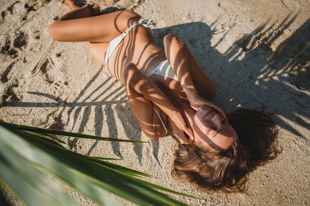 Jeune femme, pose, sur, plage sable, sous, feuille palmier